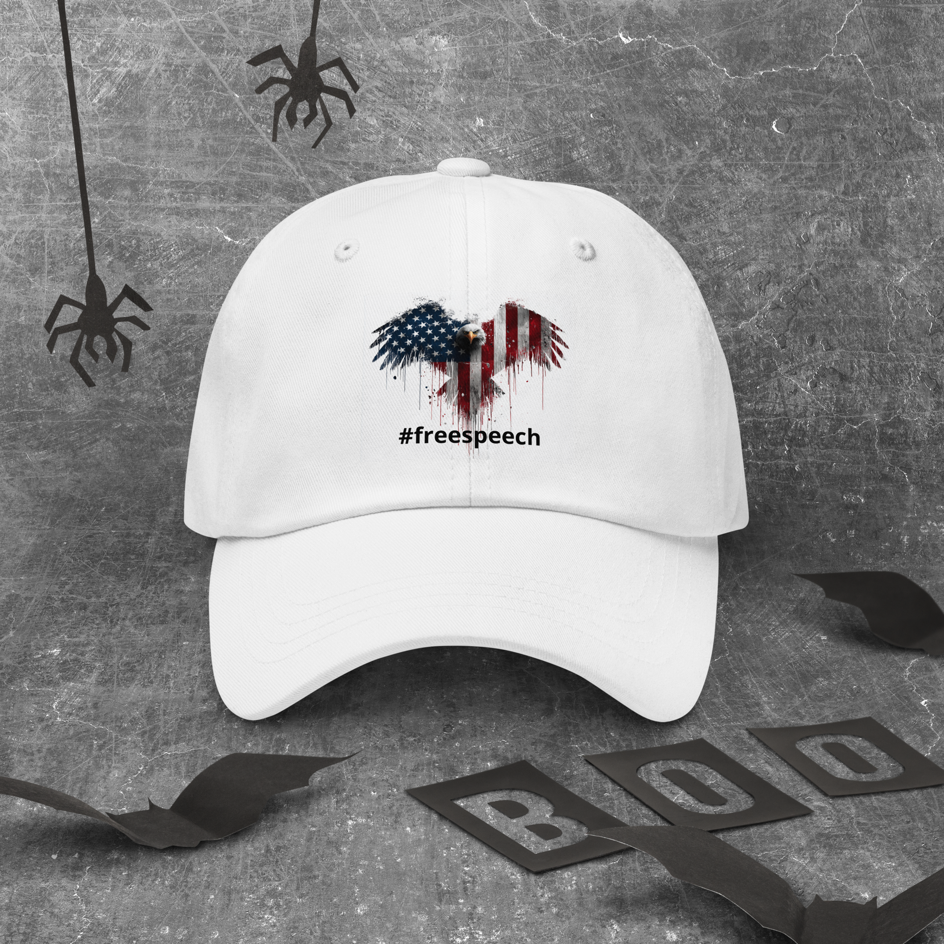 White cap with American flag design and '#freespeech' text on a textured gray background.
